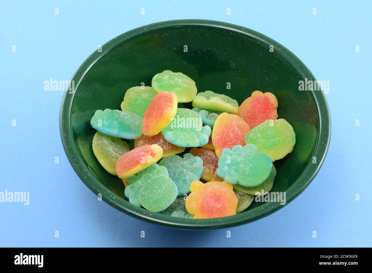 Saftgefüllte Gummy Bonbons in Meereslebewesen in grün geformt Schale auf blauem Hintergrund Stockfoto