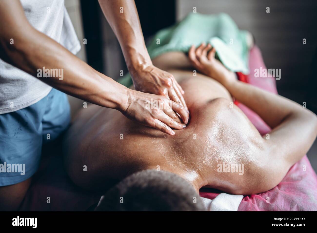 Eine Frau Physiotherapeutin, die eine Rückenmassage für einen Mann in der Arztpraxis macht. Nahaufnahme der Hände beim Massieren. Stockfoto