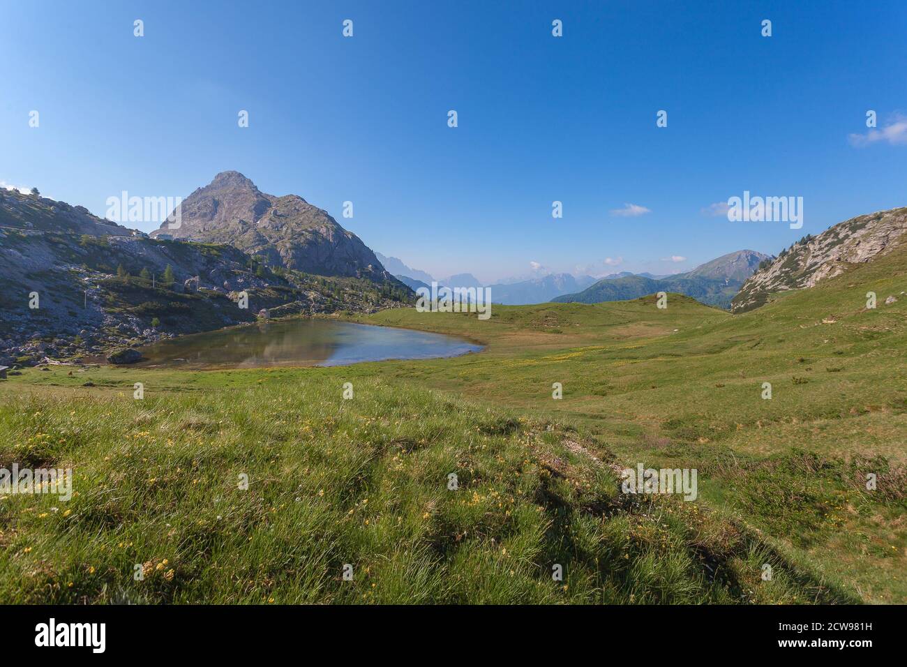 Valparolasee eingebettet in die Mitte von Wiesen mit der typischen Dolomitenlandschaft im Hintergrund, Valparola Pass, Dolomiten, Italien Stockfoto