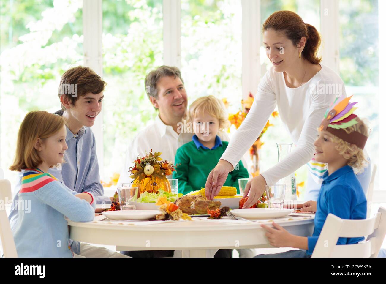 Familie mit Kindern, die Thanksgiving Abendessen essen. Geröstete truthahn- und Kürbiskuchen auf Esstisch mit Herbstdekoration. Festliche Mahlzeit für Eltern und Kinder. Stockfoto