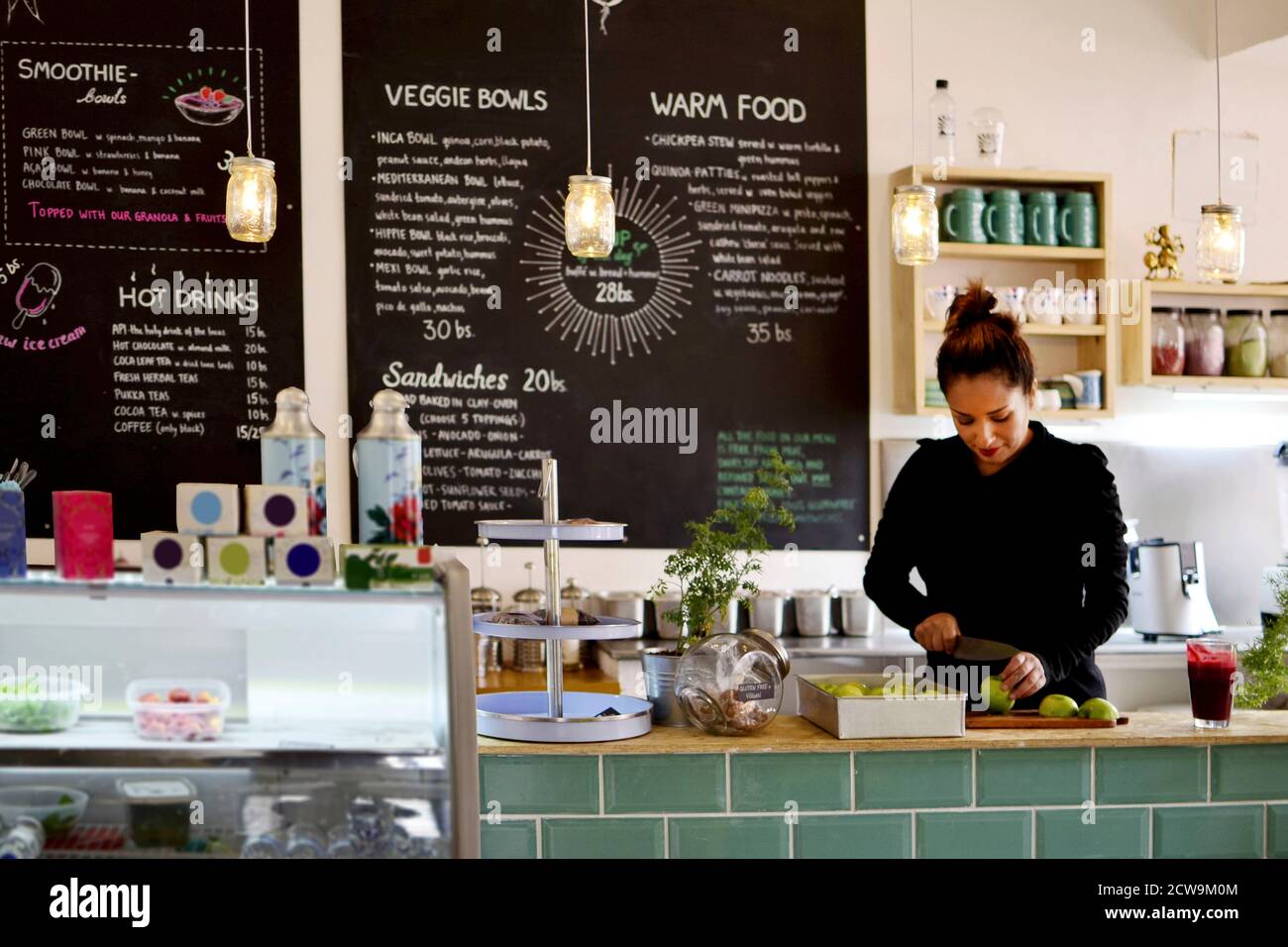 Ein engagierter Mitarbeiter oder Geschäftsinhaber bereitet sorgfältig Lebensmittel hinter der Theke eines modernen Cafés oder Restaurants mit gesunder Ernährung zu. Stockfoto