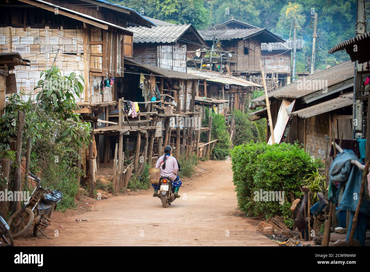 Ein kleines ländliches Dorf, ein Bergstämme Dorf in Chiang Mai Thailand, Häuser aus Holz und Bambus, und eine unbefestigte Straße mit einem Motorrad. Stockfoto