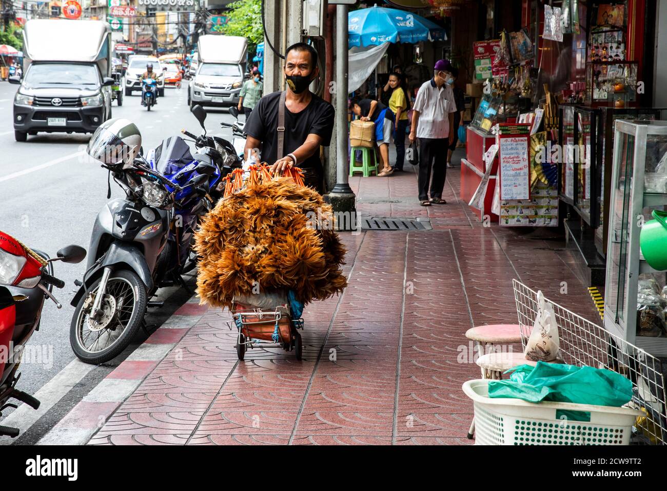 Ein Mann, der Besen verkauft, schiebt seinen Produktwagen auf einem Bürgersteig in Bangkoks Chinatown. Stockfoto