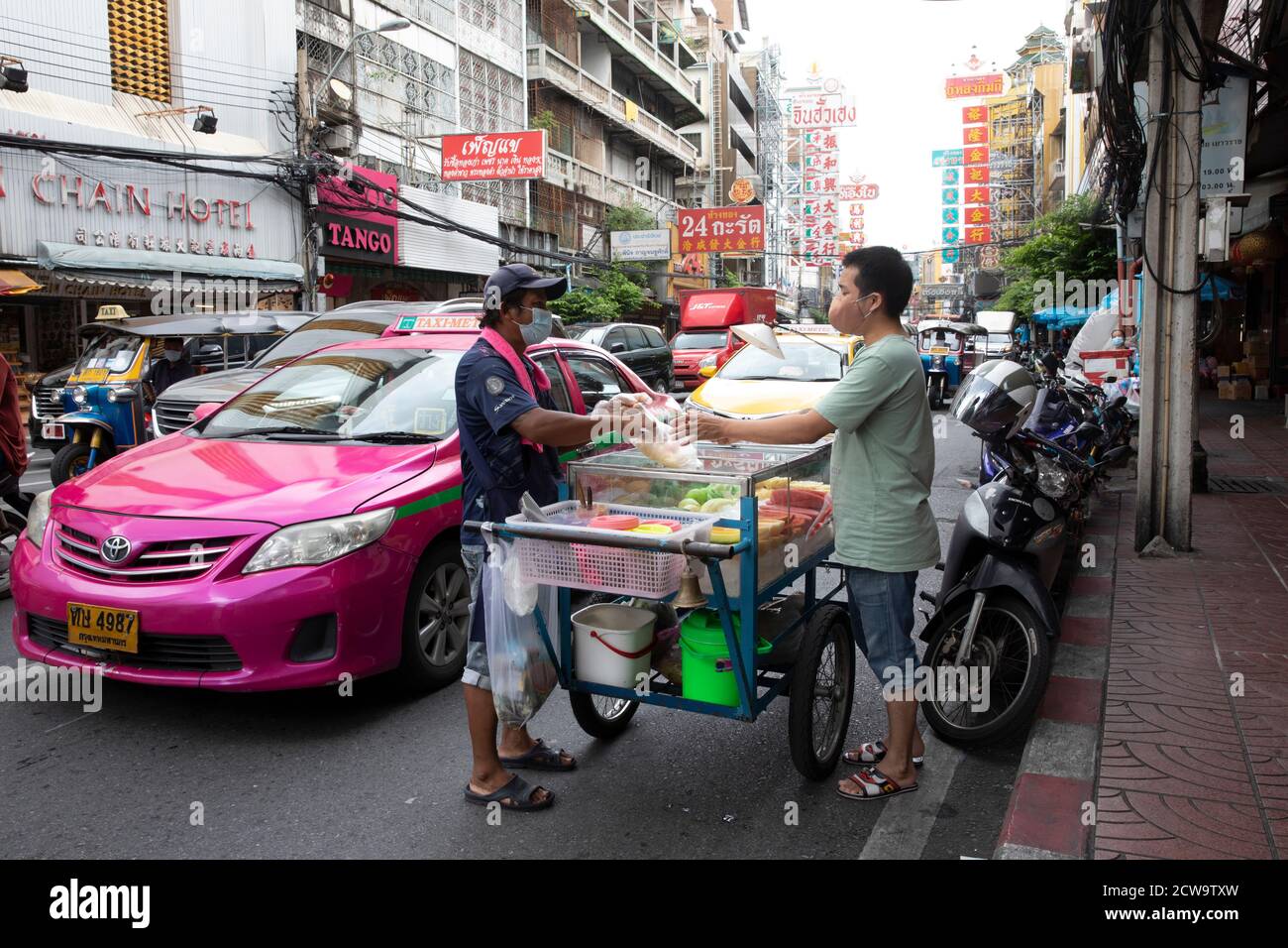 Ein Verkäufer verkauft Obst von seinem Wagen an einen Pendler in Bangkoks Chinatown während der Nachmittagsverkehrszeit. Stockfoto