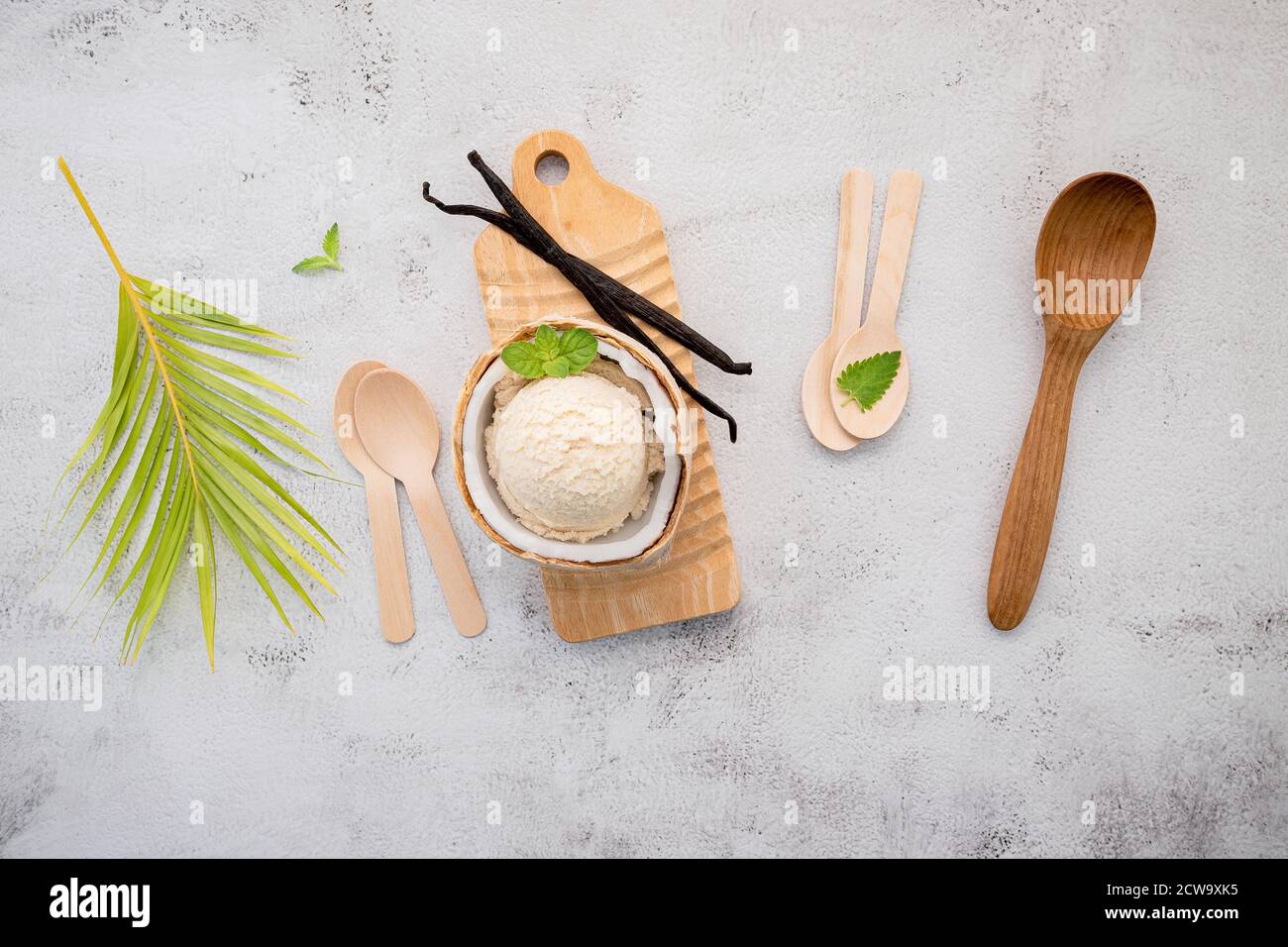 Kokoseis Aromen in der Hälfte der Kokosnuss Setup auf weißem Stein Hintergrund. Sommer und Süße Menükonzept. Stockfoto