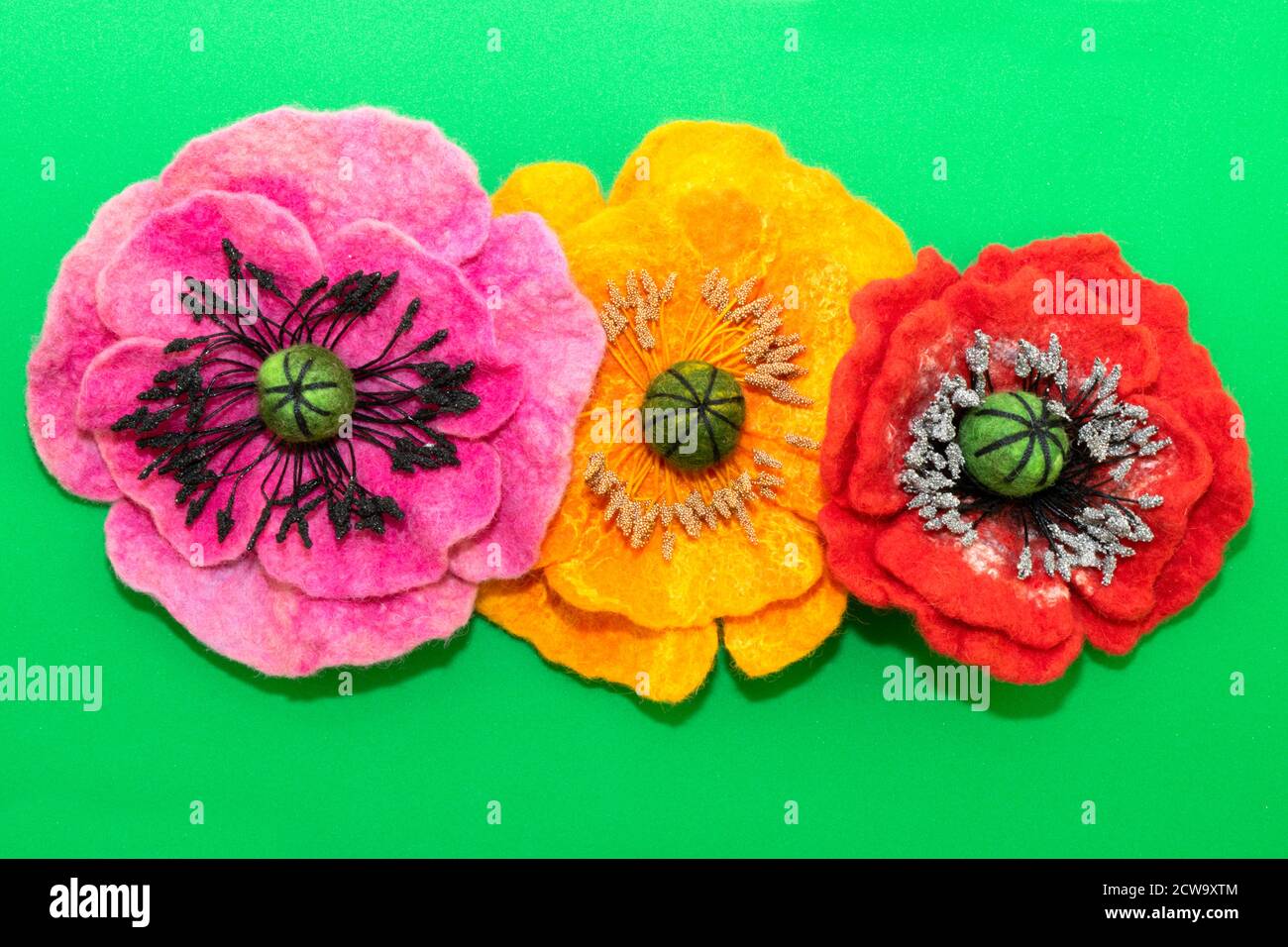 Handgemachtes Filz, Blumen, drei Filzblumen auf grünem Hintergrund Stockfoto