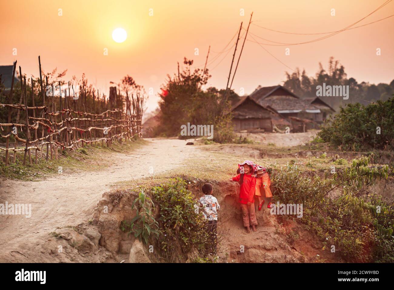 Dien Bien, Vietnam - 26. FEBRUAR 2012: Glückliche vietnamesische kleine Mädchen und Jungen spielen auf dem trockenen Kanal in der Nähe des alten Dorfes bei Sonnenuntergang. Dien Bien Phu. Stockfoto