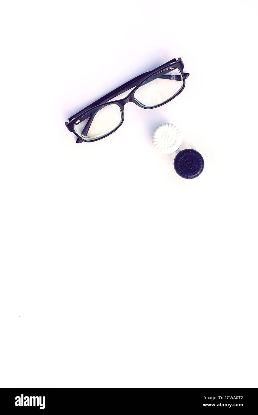 Draufsicht auf schwarz gerahmte Brillen und Kontaktlinsen im Container auf weißem Hintergrund. Stockfoto