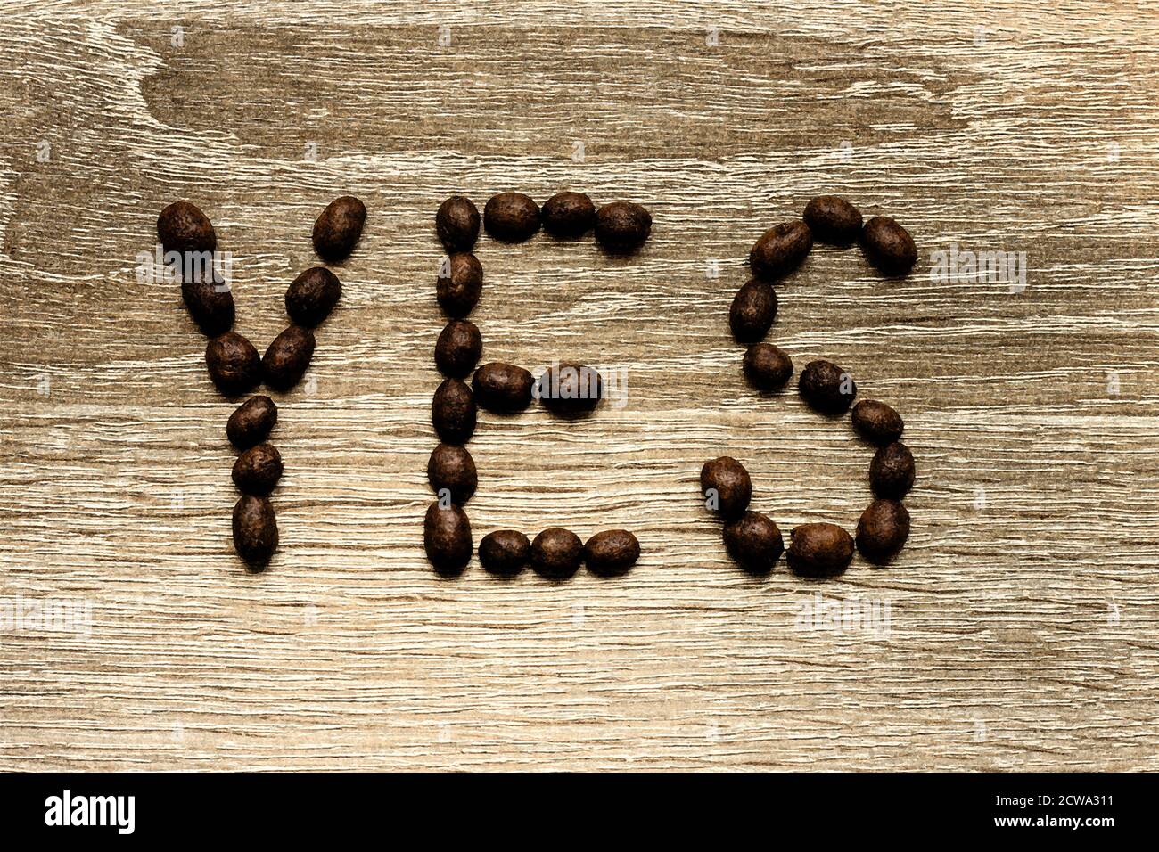 Das Wort 'Ja' wurde mit gerösteten arabica-Kaffeebohnen auf einem Holztisch ausgelegt. Stockfoto