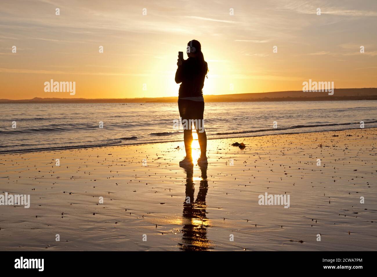 Portobello, Edinburgh, Schottland, Großbritannien. 29. September 2020. Schöner Sonnenaufgang, im Bild: Diese Joggerin musste innehalten, um die wunderschöne Szene aufzunehmen und sie auf ihrem Handy zu fotografieren. Quelle: Arch White/Alamy Live News. Stockfoto