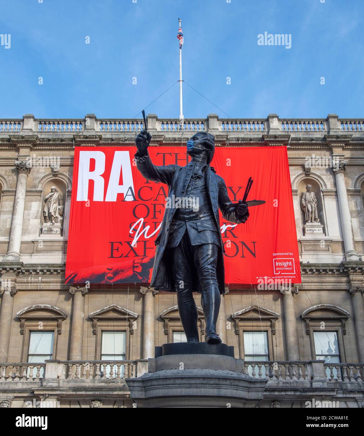 Statue von Sir Joshua Reynolds mit Covid-19 Gesichtsmask vor der Royal Academy of Arts bei der Eröffnung der RA Sommer Winter Ausstellung 2020. Stockfoto