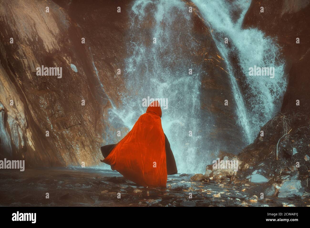 Rot getarnte Figur vor einem mächtigen Wasserfall Stockfoto