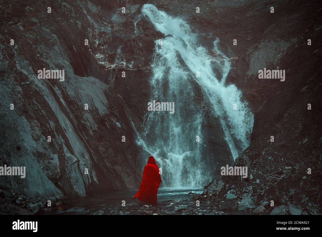 Rot getarnte Person, die einen mächtigen Wasserfall sieht Stockfoto