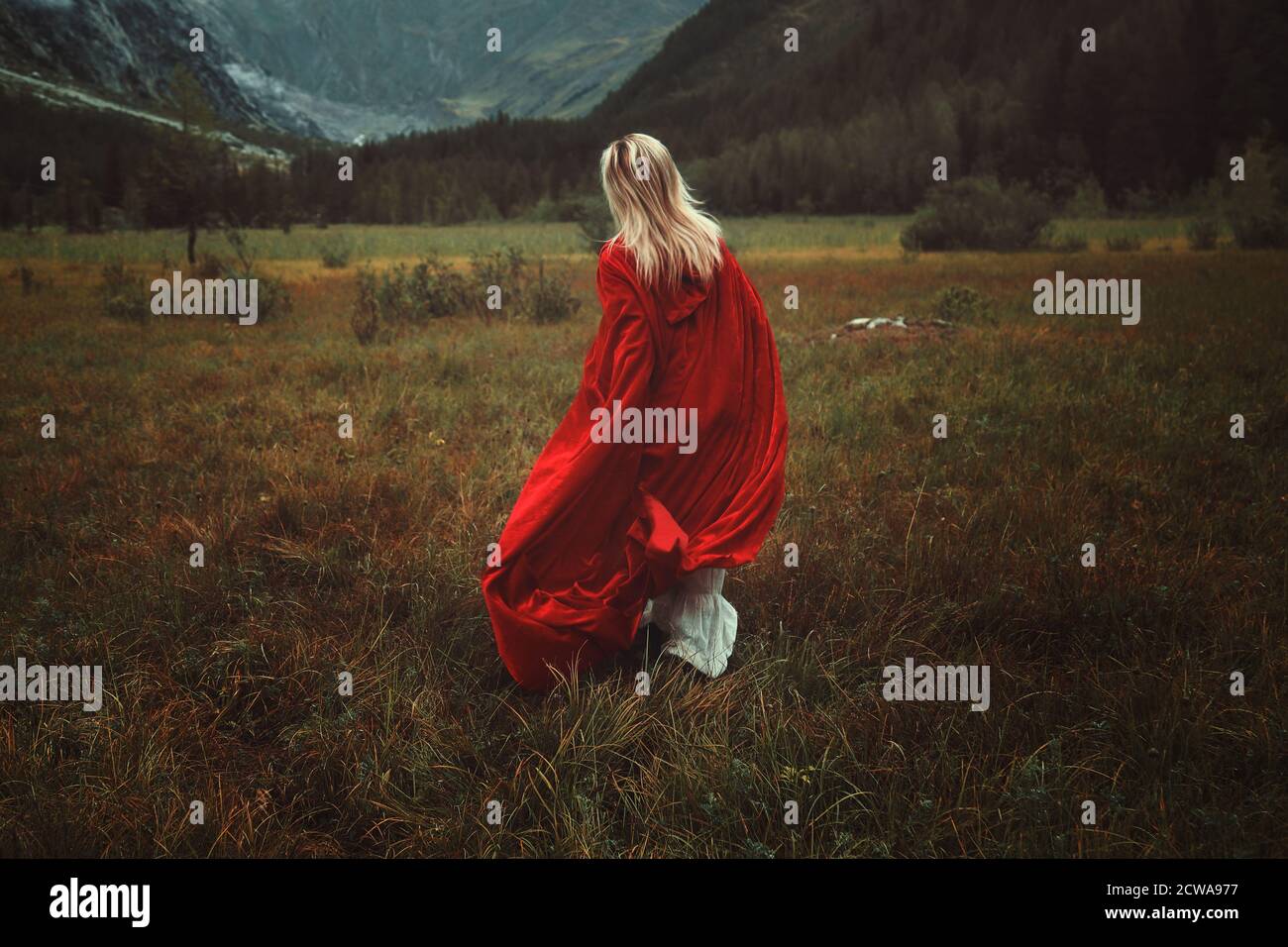 Frau mit rotem Mantel läuft in einem trostlosen Land Stockfoto