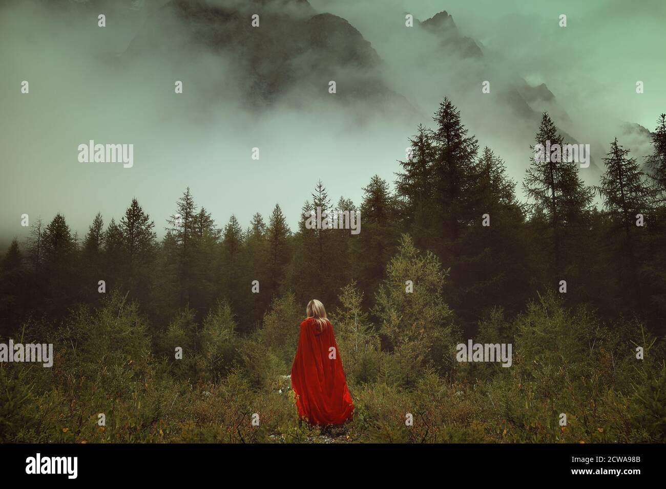 Frau mit rotem Mantel in einem nebligen Wald Stockfoto