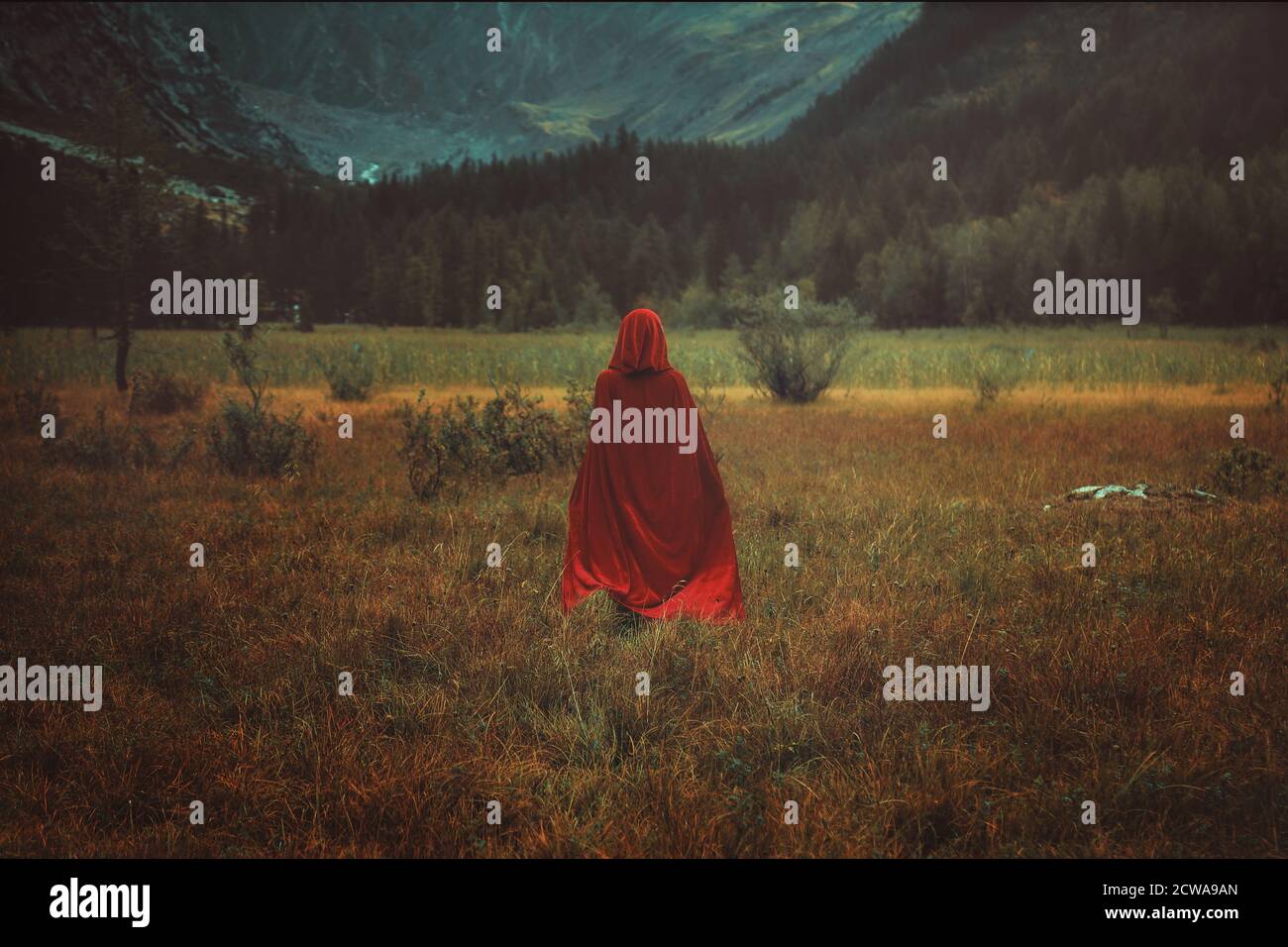 Frau mit rotem Mantel in einem Bergtal. Lackeffekt Stockfoto