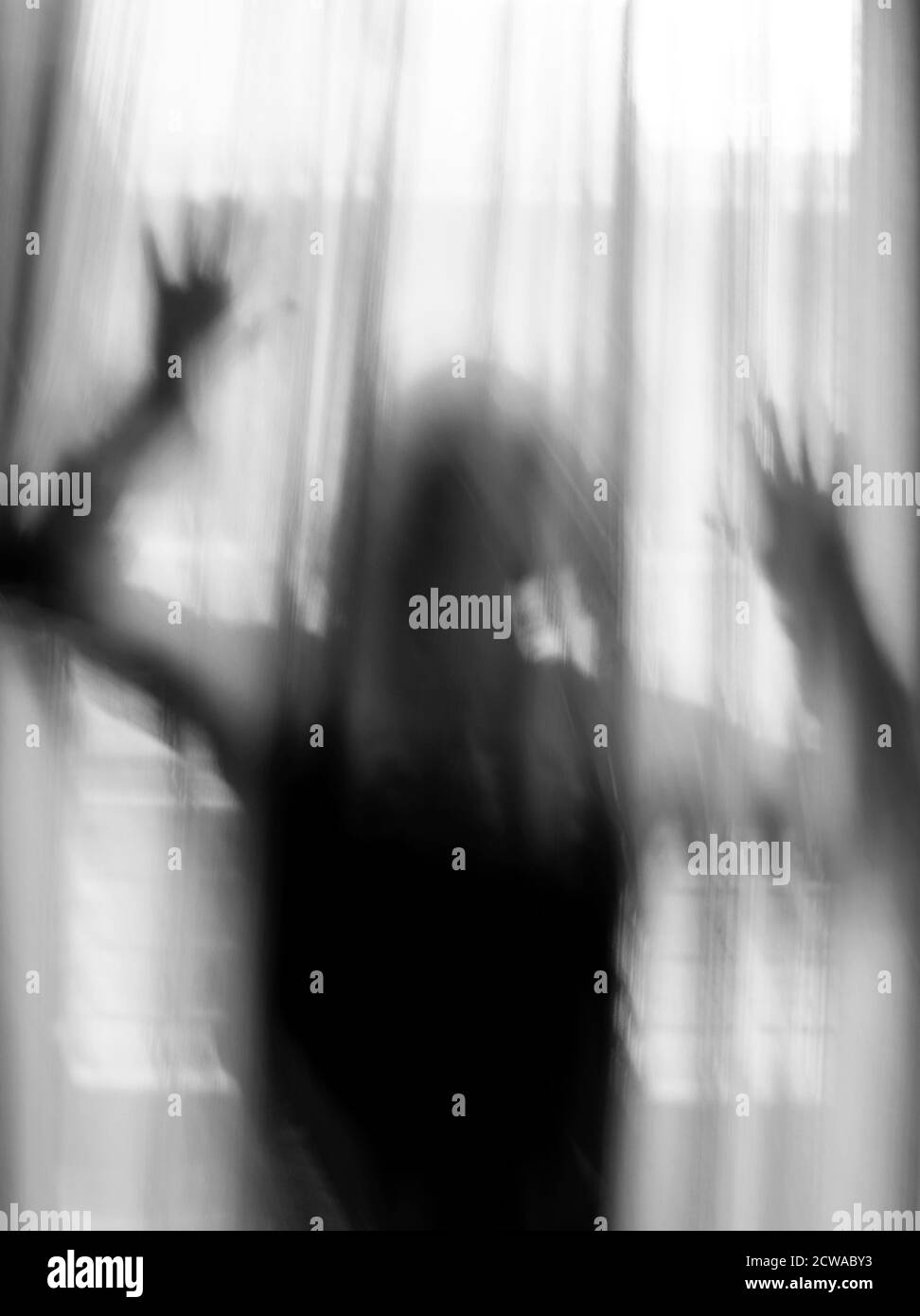 Schwarz-weißer Schatten eines Mädchens, durch den Vorhang bei hellem Tageslicht gesehen. Stockfoto