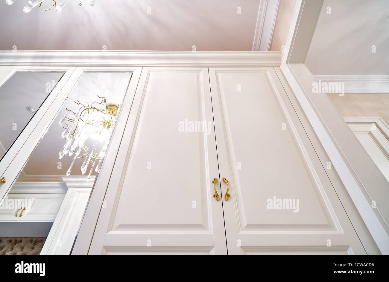 Klassischer weißer Kleiderschrank mit Spiegeltüren in modernem, hellem Flur. Klassische Möbel Stockfoto