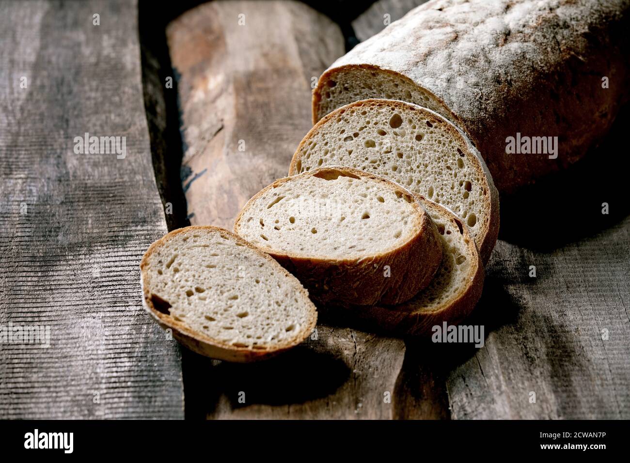 In Scheiben geschnittenes Vollkorn-Roggen-Weizen-Bio-Brot auf altem Holzhintergrund. Stockfoto