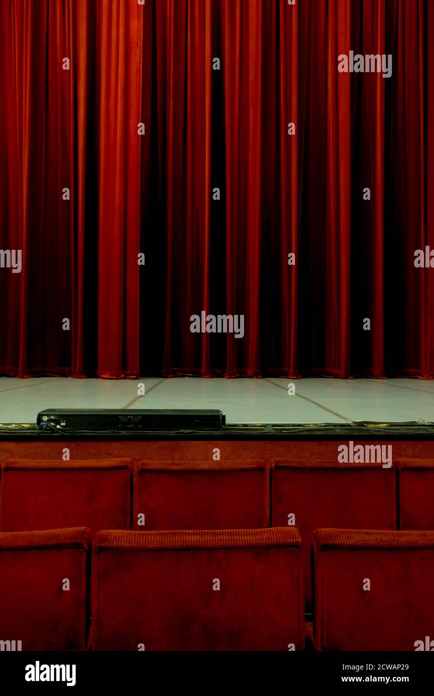 Rote Theatersitze sehen auf einen roten geschlossenen Vorhang warten Damit die Performance beginnt Stockfoto