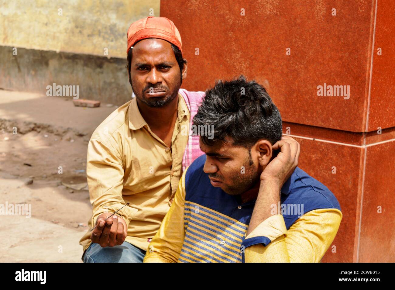 Ein Mann zeigt und Reinigung Kundenohr, Ohrenschmalz für Geld auf verkehrsreichen Straße in chandani chowk, alt delhi, indien. Stockfoto