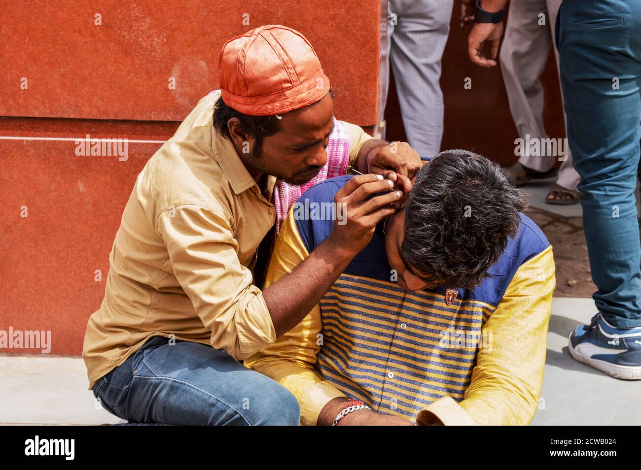 Ein Mann reinigt Kundenohr, Ohrenschmalz für Geld auf vielbefahrenen Straße in chandani chowk, alt delhi, indien. Stockfoto