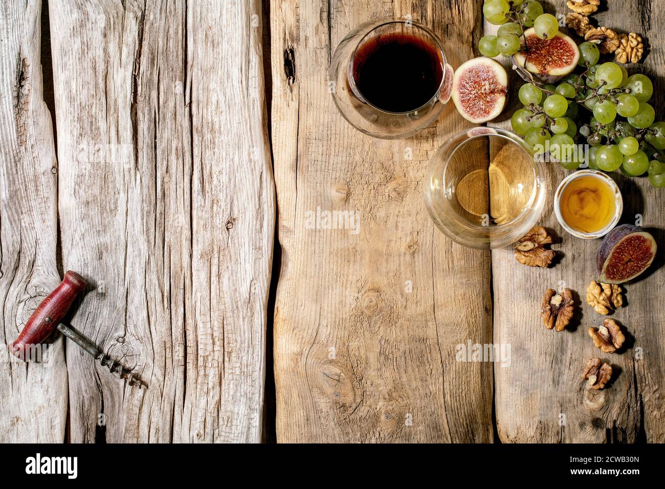 Gläser von Rot- und Weißwein mit Trauben, Feigen, Ziegenkäse und Walnüssen auf altem Holzhintergrund. Flach liegend, Kopierplatz Stockfoto