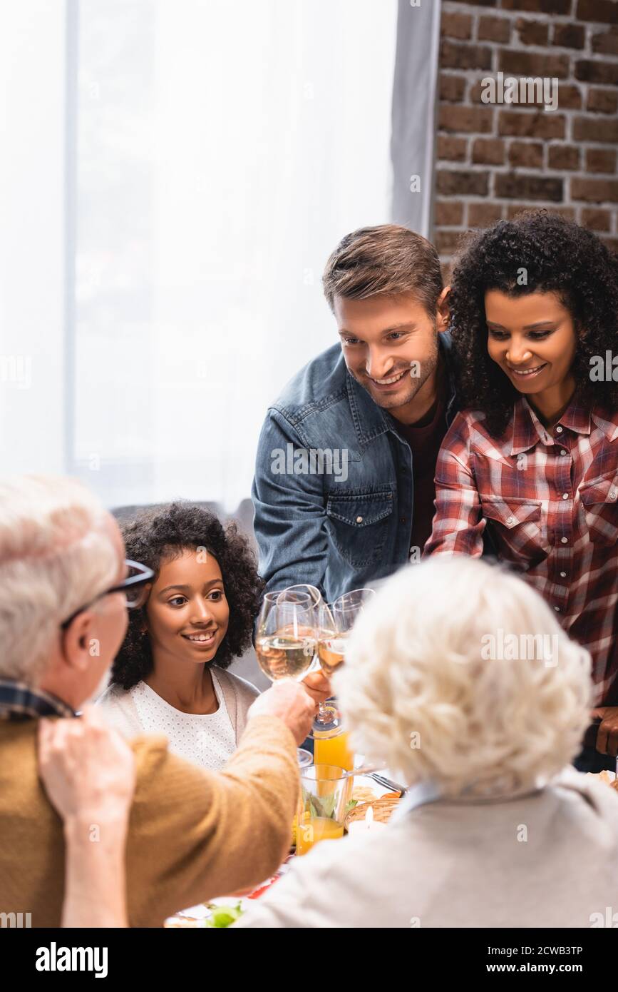 Selektiver Schwerpunkt der multiethnischen Familie Toasting mit Wein während der Danksagung Stockfoto
