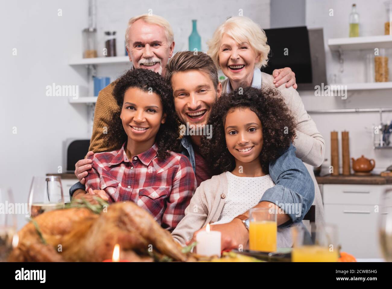 Selektiver Fokus auf multikulturelle Familie, die beim Feiern auf die Kamera schaut erntedankfest Stockfoto