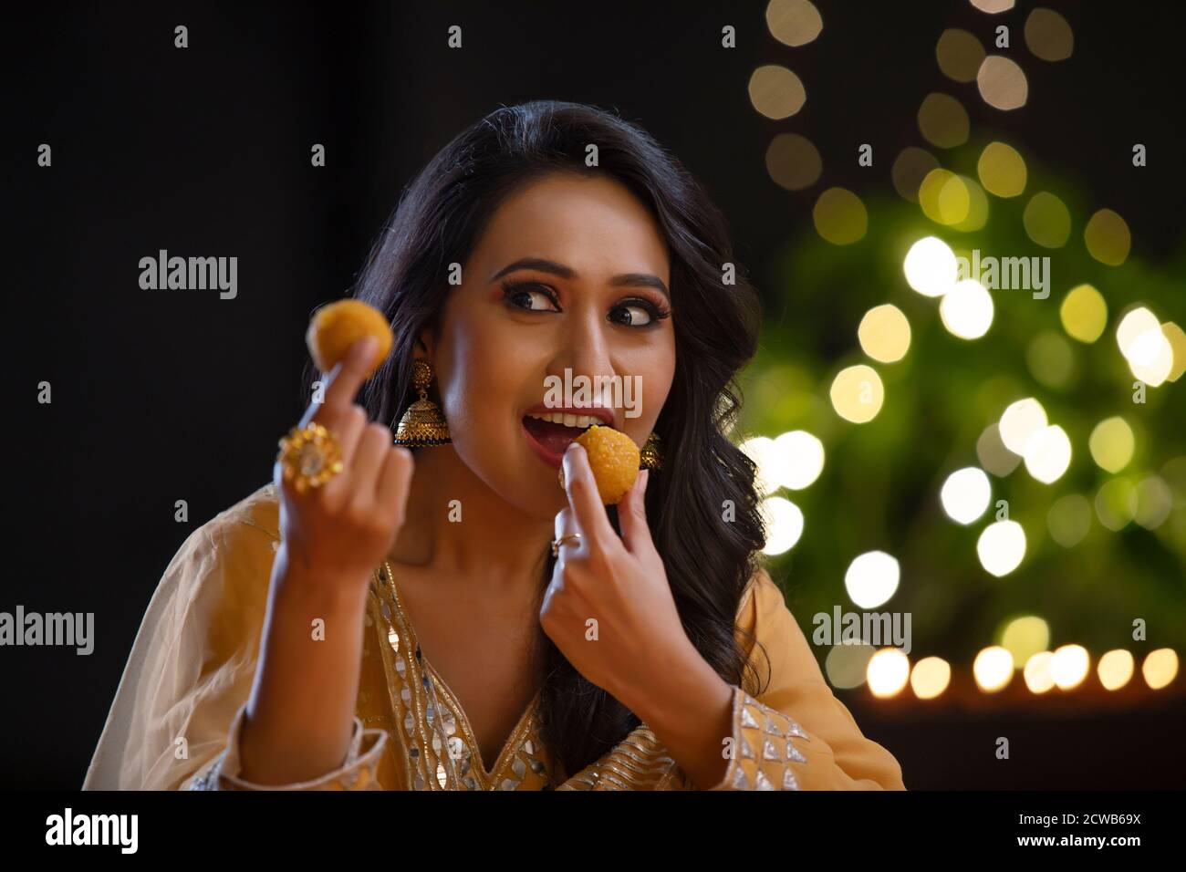 Lady essen ladoo aus einer Hand und Blick auf eine andere Stockfoto