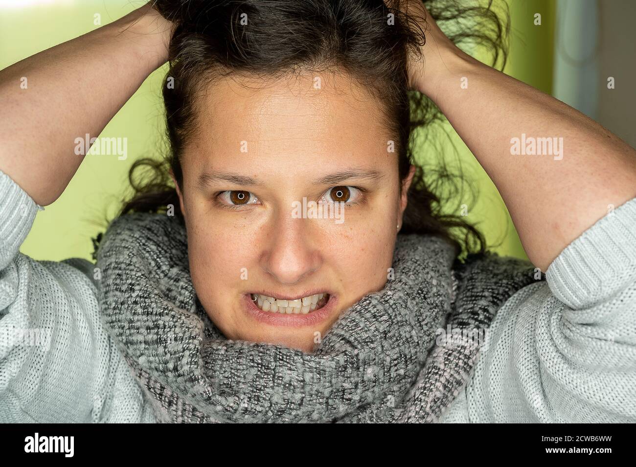 Eine junge Frau mit einem wütenden Blick zieht an ihren Haaren. Stockfoto
