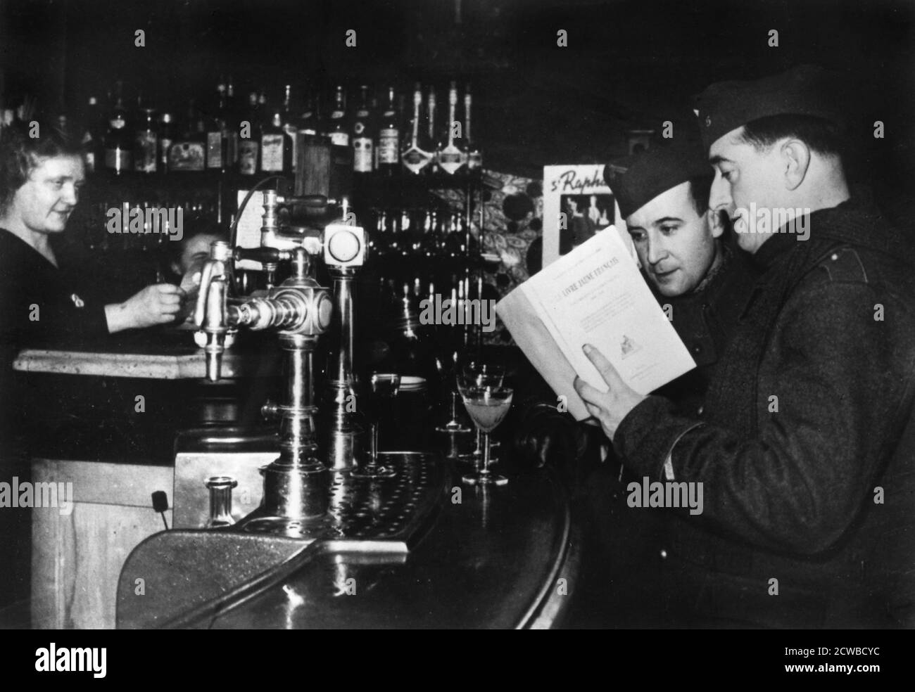 Zwei französische Soldaten auf Urlaub in einem Café, c1939-1940. Sie sehen sich eine Kopie des Buches Le Livre Jaune Francais an, das vom französischen Außenministerium über diplomatische Verhandlungen zwischen Großbritannien, Frankreich, Polen und Deutschland vor Ausbruch des Zweiten Weltkriegs veröffentlicht wurde Der Fotograf ist unbekannt. Stockfoto