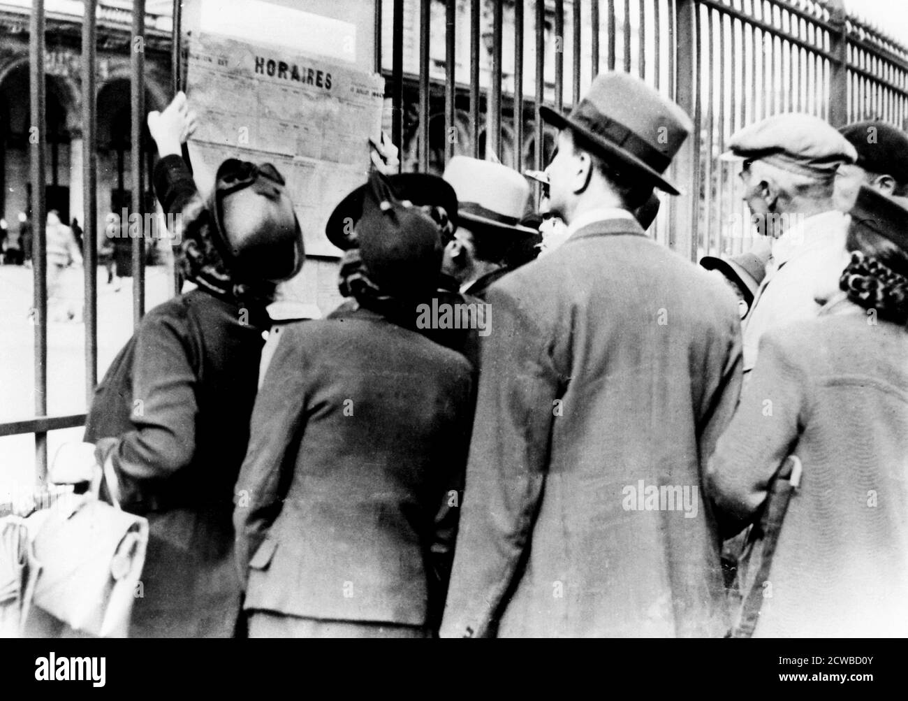 Flüchtlinge studieren einen Zugfahrplan, Gare de l'Est, Paris, Juli 1940. Menschen, die die deutschen Invasoren geflohen waren, bereiten sich darauf vor, nach der Niederlage Frankreichs in ihre Häuser zurückzukehren. Der Fotograf ist unbekannt. Stockfoto