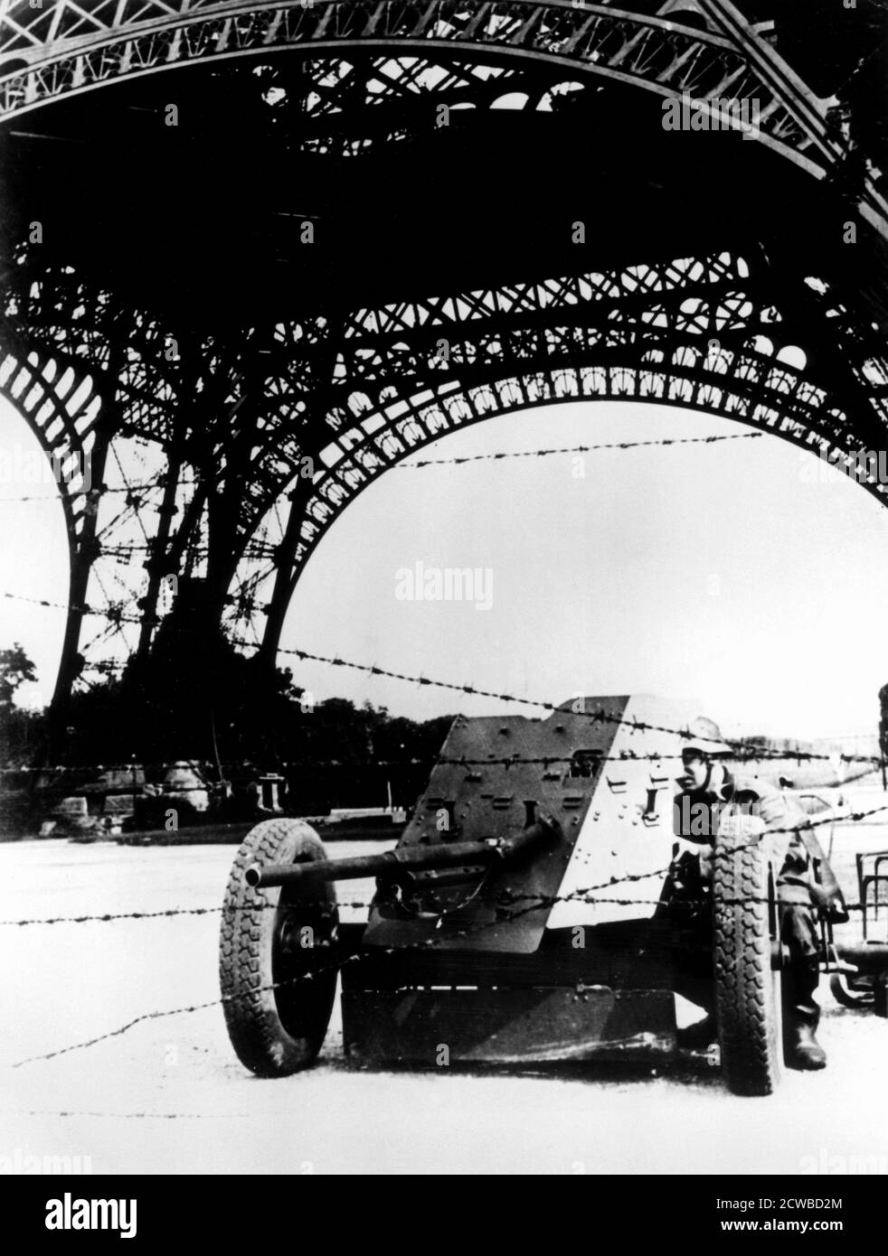 Stacheldraht und Panzerabwehrkanone unter dem Eiffelturm, deutsch besetzt Paris, 1940-1944. Der Fotograf ist unbekannt. Stockfoto