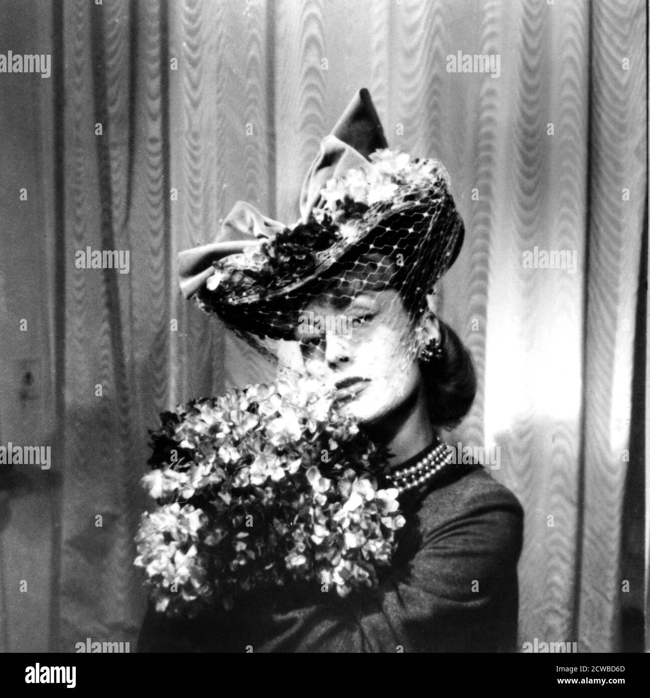 Frau mit Hut und Schleier, mit Blumenstrauß, Paris, 1943. Der Hut ist von dem französischen Modedesigner Jacques Fath. Der Fotograf ist unbekannt. Stockfoto