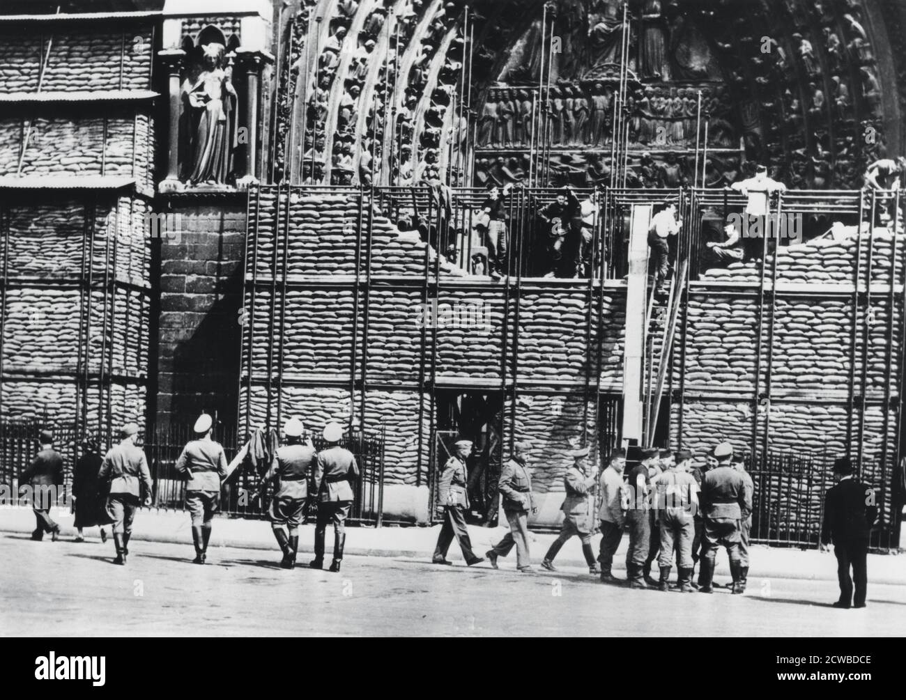 Reinigung des Sandsackschutzes von der Fassade von Notre Dame, deutsch-besetzte Paris, 1940. Paris überlebte die Nazi-Invasion relativ unbeschadet, nachdem die Regierung sie zu einer offenen Stadt erklärt und sie den Deutschen überlassen hatte. Der Fotograf ist unbekannt. Stockfoto