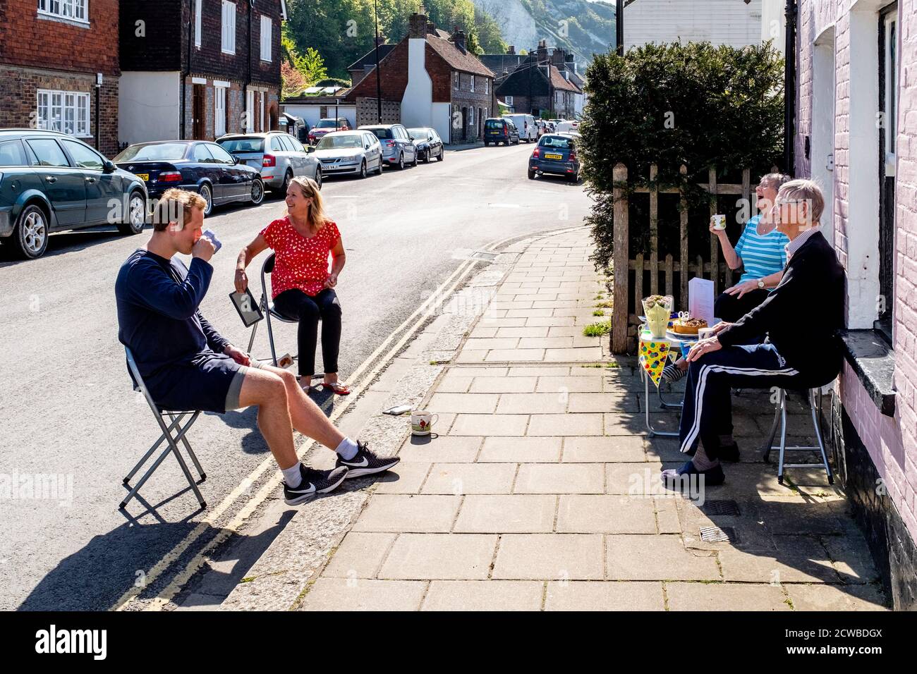 Ein älteres Paar sitzt außerhalb ihres Hauses mit ihrer Tochter und ihrem Enkel und praktiziert soziale Distanzierung während der Corona Virus Pandemie. Lewes, Großbritannien. Stockfoto
