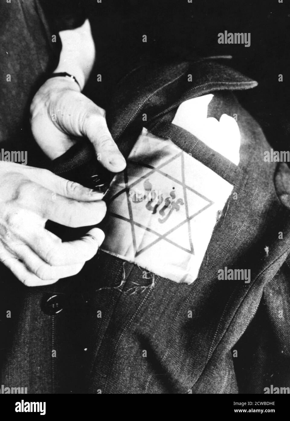 Nähen des gelben Sterns, der einen Juden identifiziert, auf eine Jacke, deutsch-okkupiert Paris, 1942. Das Leben für französische Juden war unter der Nazi-Besatzung unterdrückend. Kollaborateure im besetzten Teil des Landes und in dem vom Vichy-Regime kontrollierten Gebiet arbeiteten enthusiastisch bei der Verfolgung zusammen. Die jüdische Bevölkerung war ab 1941 gezwungen, den gelben Stern auf ihrer Kleidung zu tragen. In den Jahren 1942-1944 wurden 76,000 Juden in Konzentrationslager deportiert. Nur 2500 überlebten. Der Fotograf ist unbekannt. Stockfoto