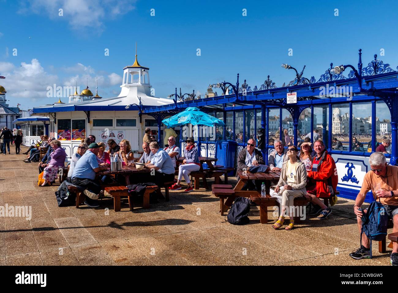 Leute, die vor EINEM Cafe am Eastbourne Pier sitzen und die Eastbourne Airshow, Eastbourne, East Sussex, Großbritannien, beobachten Stockfoto
