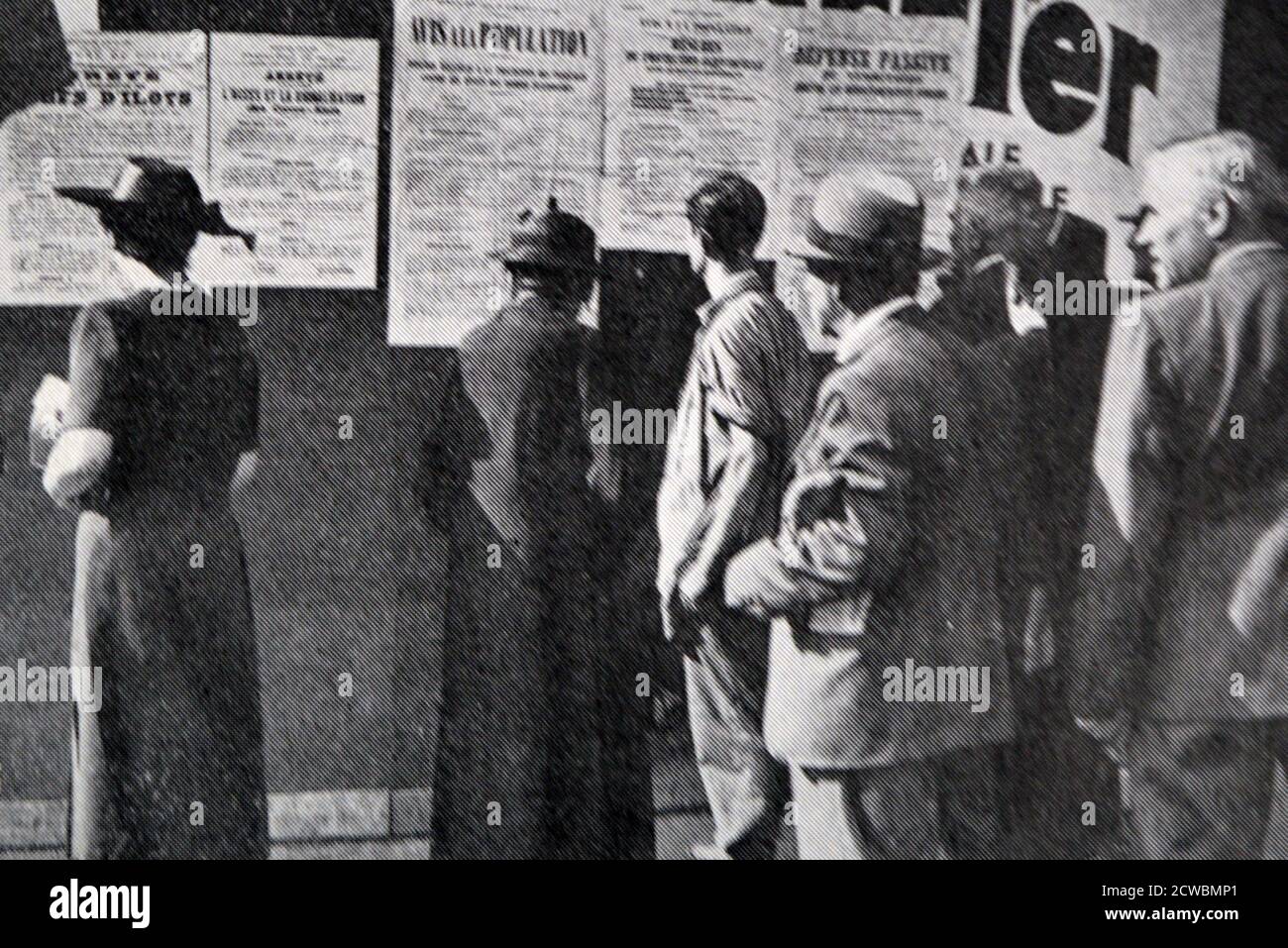 Schwarz-Weiß-Foto über die ersten Tage des Krieges in Paris; Menschen lesen Plakate über passive Verteidigung an einer Wand angebracht. Stockfoto