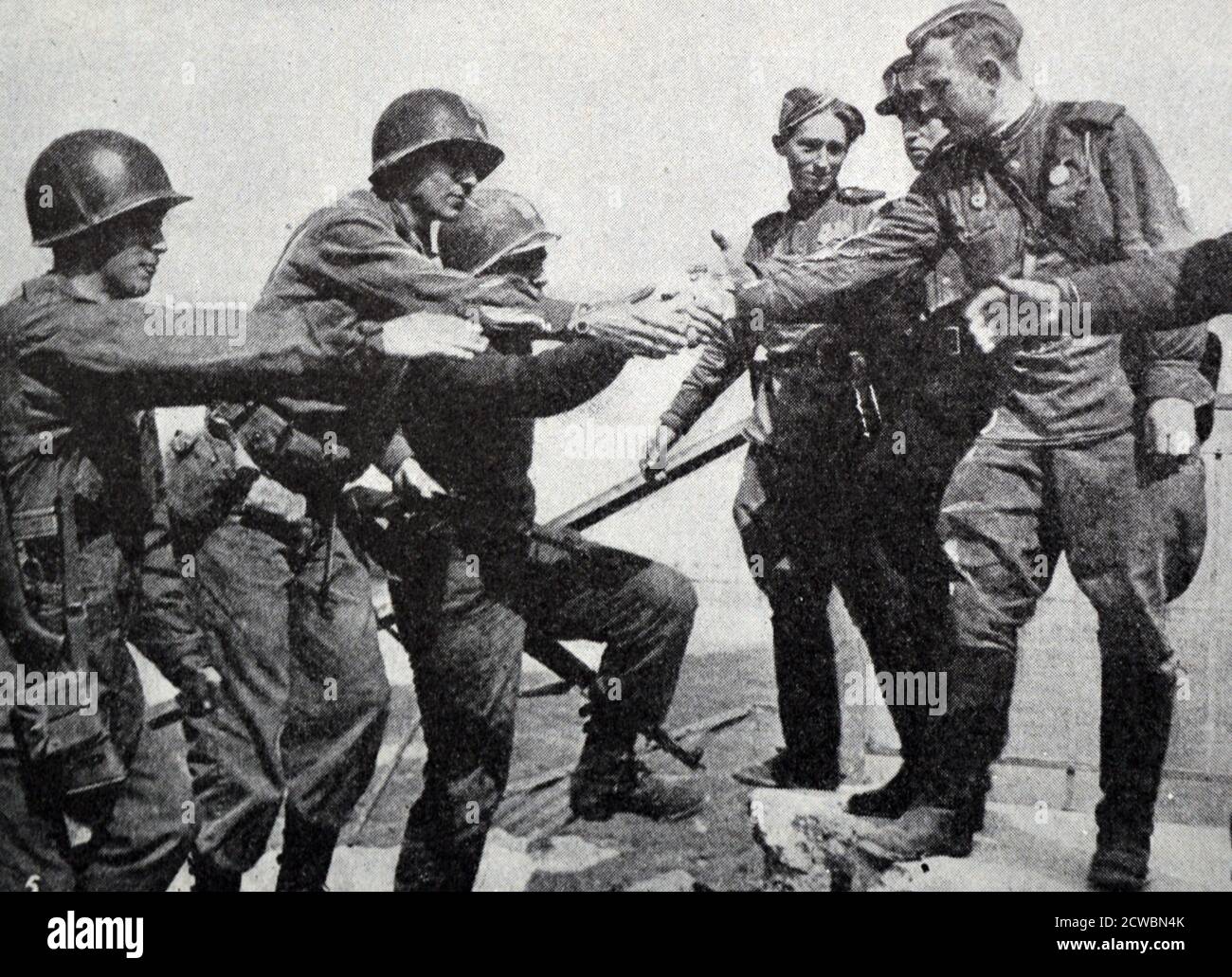 Schwarz-Weiß-Fotografie des Zweiten Weltkriegs (1939-1945) zeigt das Ende des Krieges in Europa; amerikanische und russische Truppen schütteln sich die Hände, nachdem sie sich auf der Elbe bei Torgau treffen, als Symbol für die Teilung der deutschen Streitkräfte durch die Alliierten am 26. April 1945. Stockfoto
