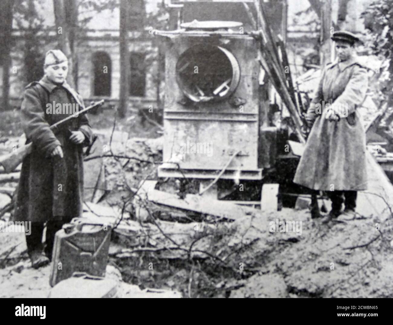 Schwarz-Weiß-Fotografie des Zweiten Weltkriegs (1939-1945) zeigt sowjetische Soldaten, die auf einen Trümmerhaufen im Berliner Kanzlerhof zeigen, wo die Überreste von Adolf Hitler (1889-1945) und seiner Frau Eva Braun (1912-1945) nach ihrem Selbstmord durch Bombenangriffe begraben werden. Stockfoto