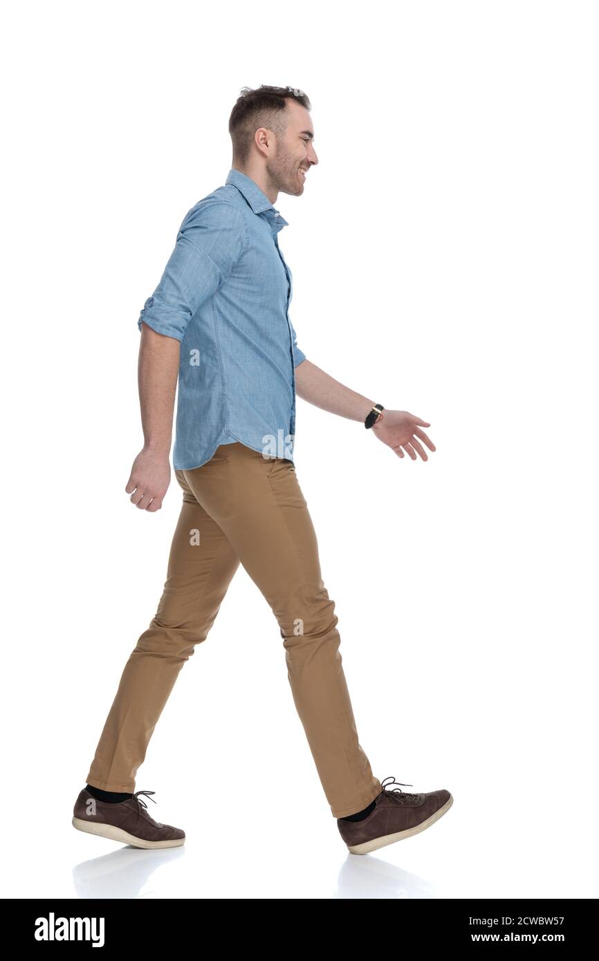 Seitenansicht des glücklichen Casual Mann lachend und trägt blaues Hemd, Schritt auf weißem Studio Hintergrund Stockfoto