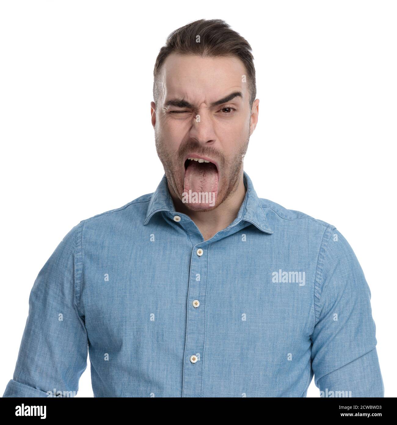 Lustige Casual Mann winken und ragen aus seiner Zunge, während das blaue Hemd, stehen auf weißem Studio Hintergrund Stockfoto