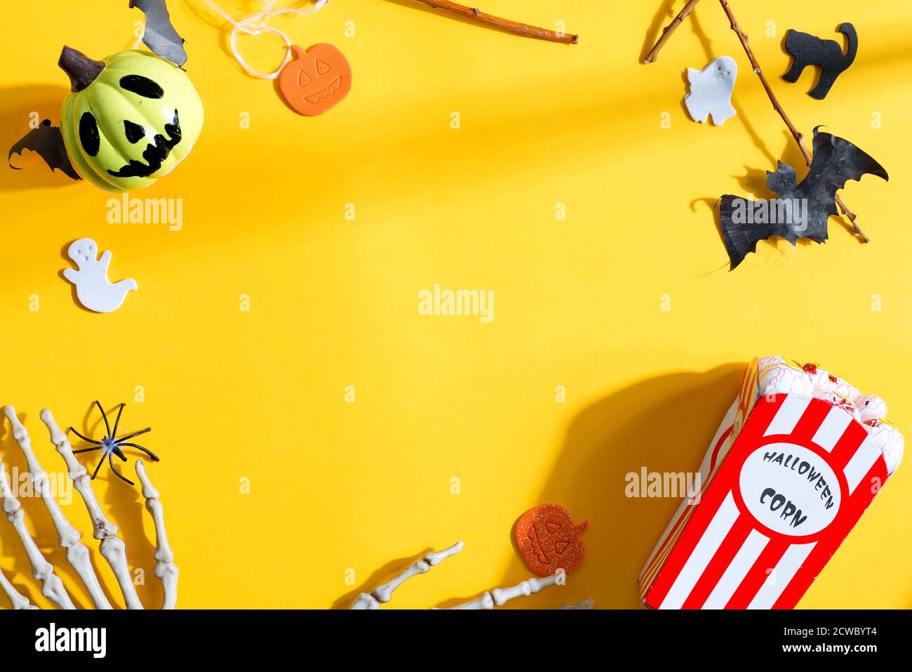 Kreativer Rahmen für Halloween-Party mit Feiertagszubehör - schneiden Sie Bastel-Kürbisse, Katzen und Geister, Skelett-Hände und Augäpfel Mais auf gelbem Backgrou Stockfoto