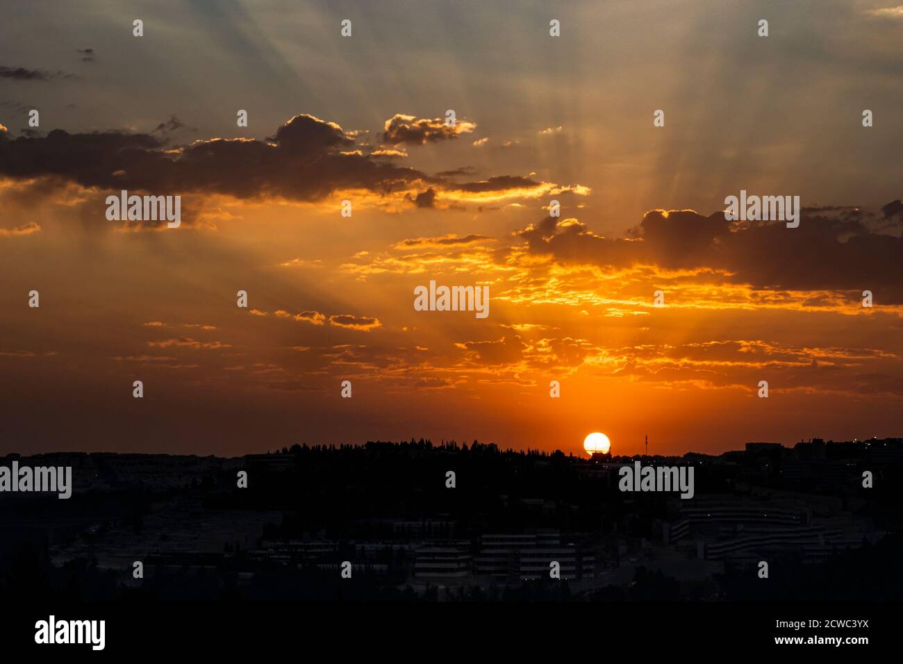 Ein wolkenvertrüber Sonnenaufgang über Jerusalem, Israel und den Judäa-Bergen. Sonnenstrahlen kommen aus den Wolken. Stockfoto