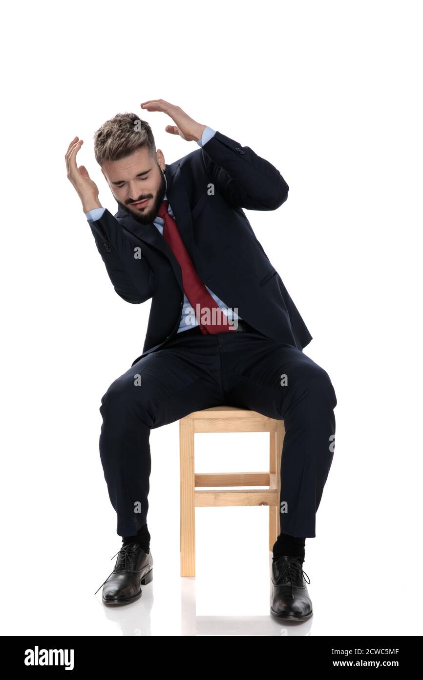 Junger Geschäftsmann in Anzug hält die Hände bis sich selbst zu schützen, sitzen isoliert auf weißem Hintergrund Stockfoto