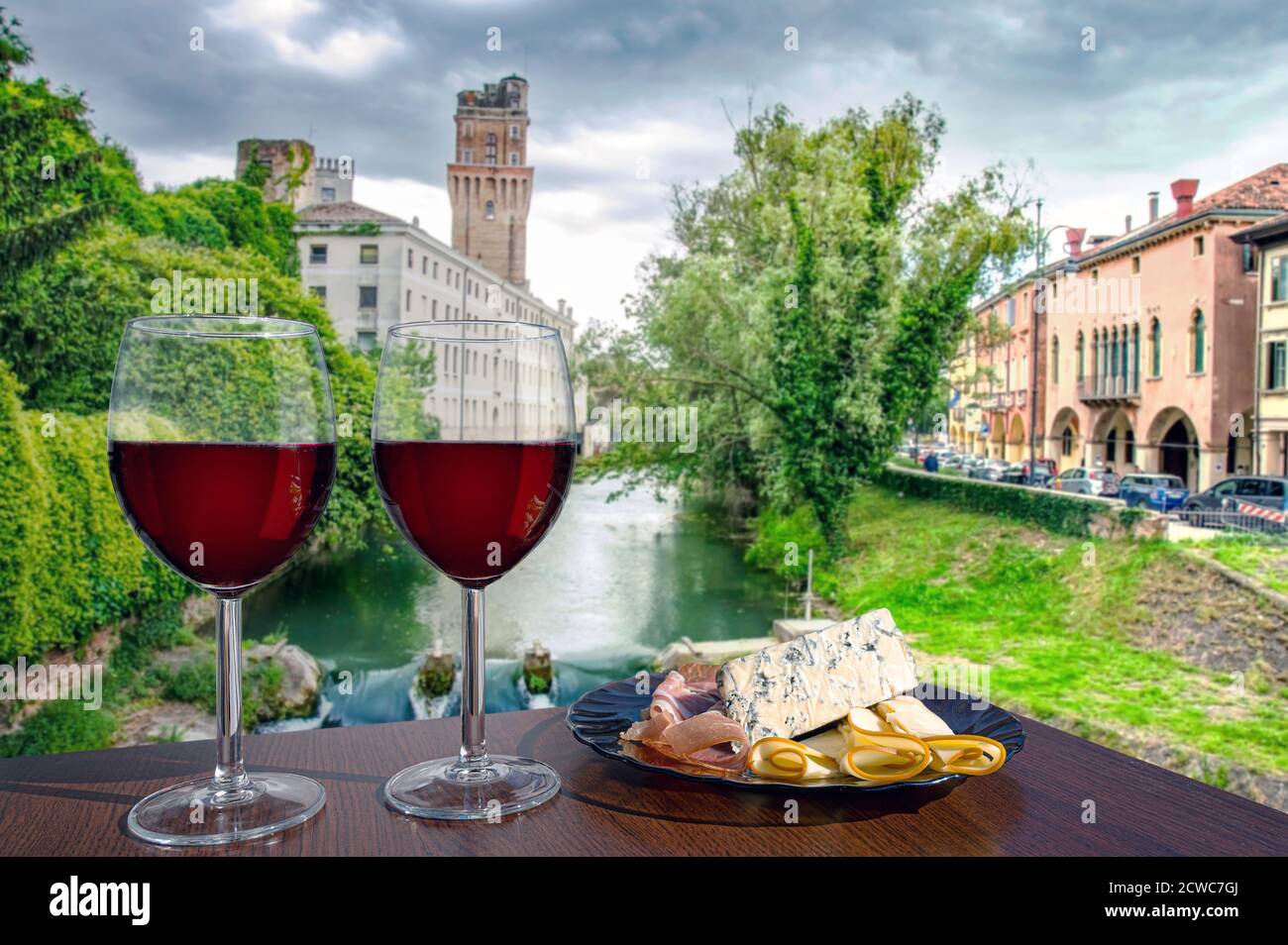 Zwei Gläser Rotwein mit Käse und Fleischsnacks mit Blick auf den Kanal in Italien. Stockfoto