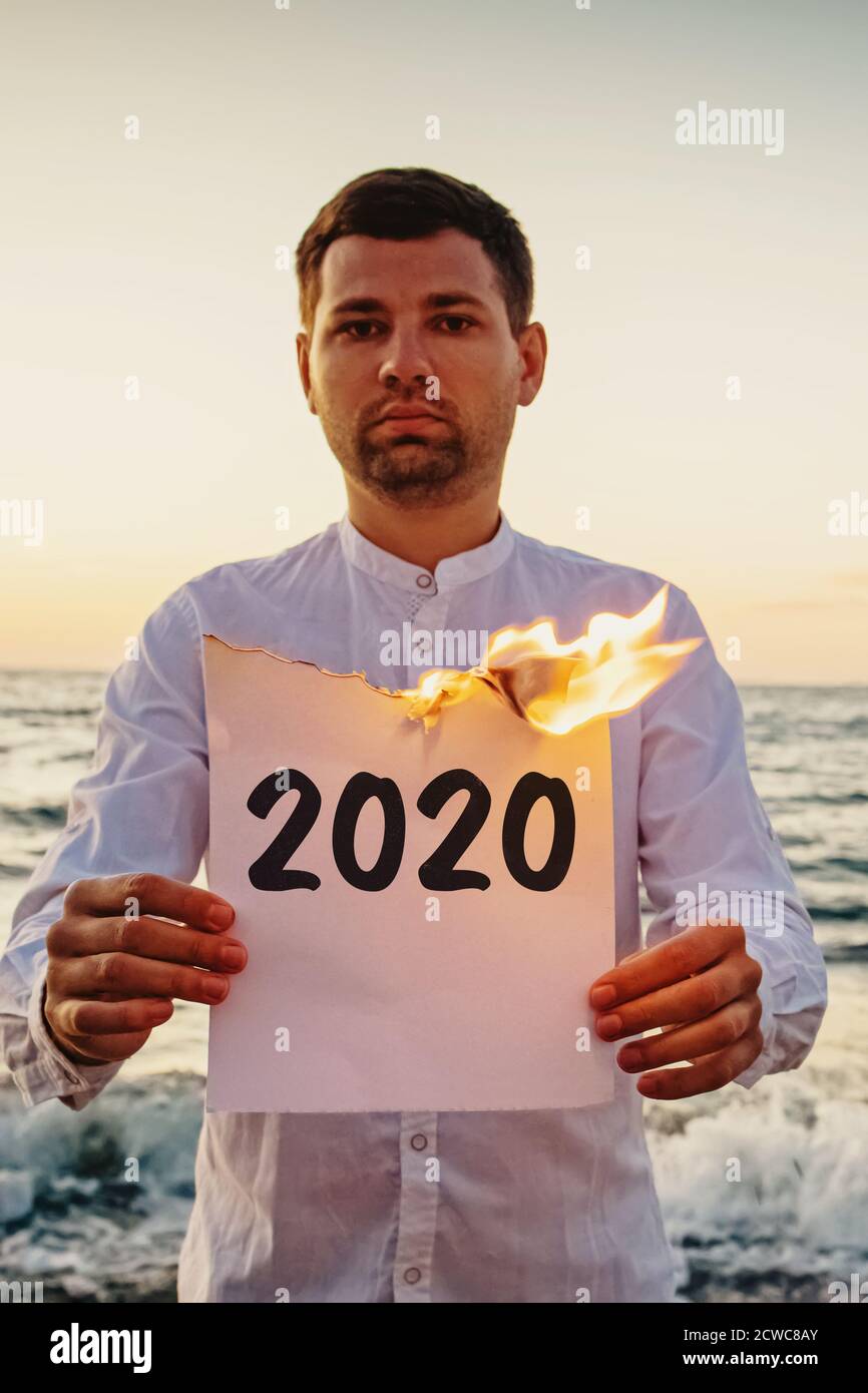 Mann, der Papier hält, das mit Text 2020 auf ihm geschrieben brennt. Stockfoto