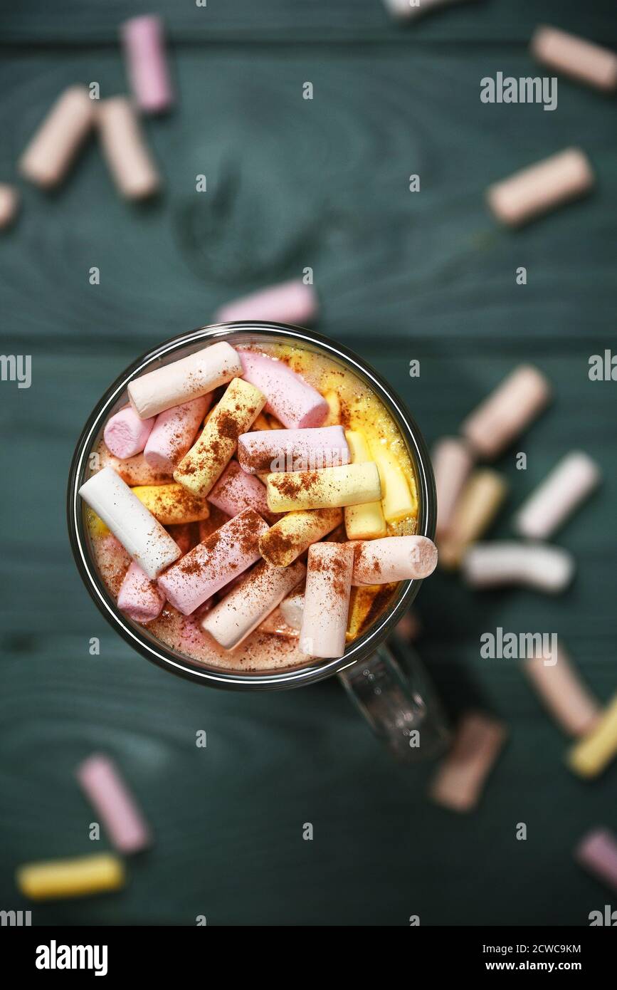 Flache Tasse mit Kaffee und Marshmallow auf grünem Schreibtisch Stockfoto